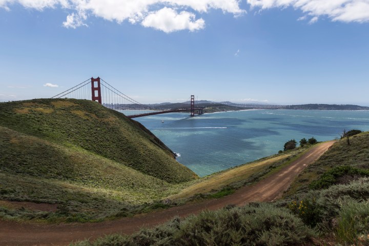 Landscape with Golden Gate Bridge, bay, hills, and cloudy sky.